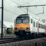 blue and orange train on rail tracks