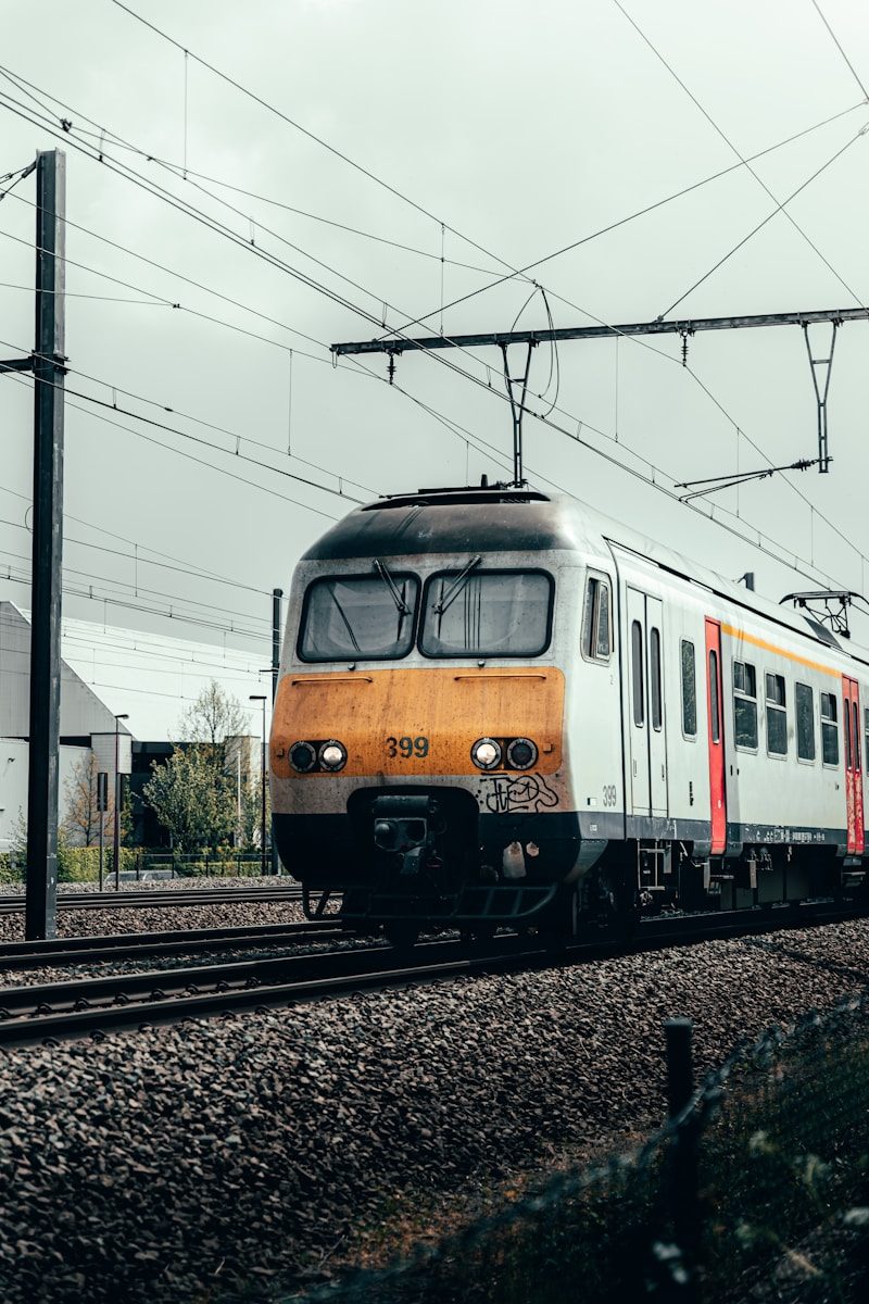 blue and orange train on rail tracks