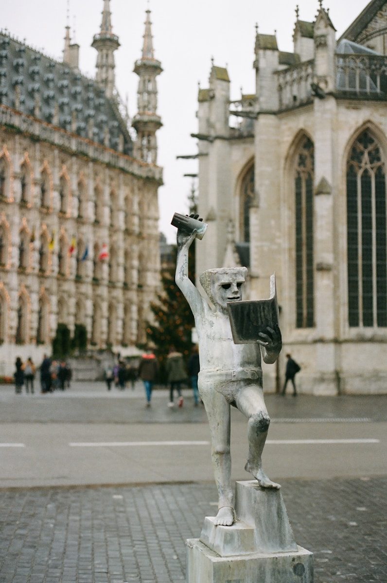 a statue of a man holding a book in front of a building